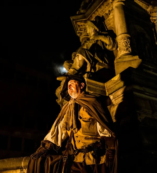 Nachtwächter steht am historischen Brunnen während einer Nachtwächtertour in Köln